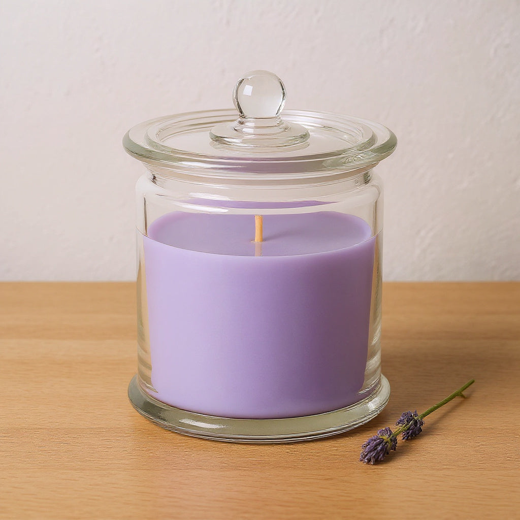 Naldony Lavender Fields soy candle in a clear glass apothecary jar on a pale oak surface with a sprig of fresh lavender